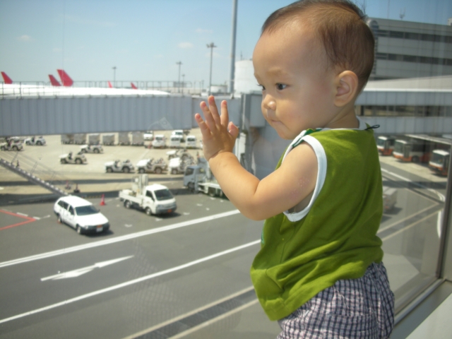 飛行場のフロアーから飛行機を見ている赤ちゃん