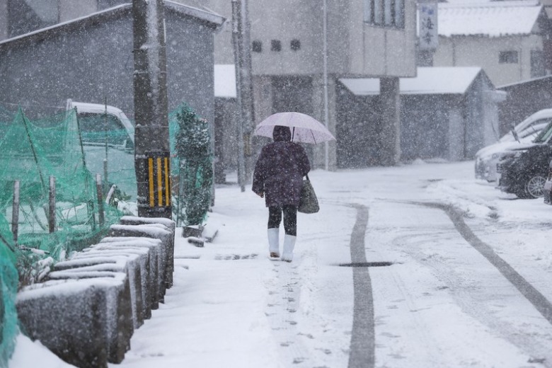 積雪の渋滞で車を諦め徒歩で移動する女性